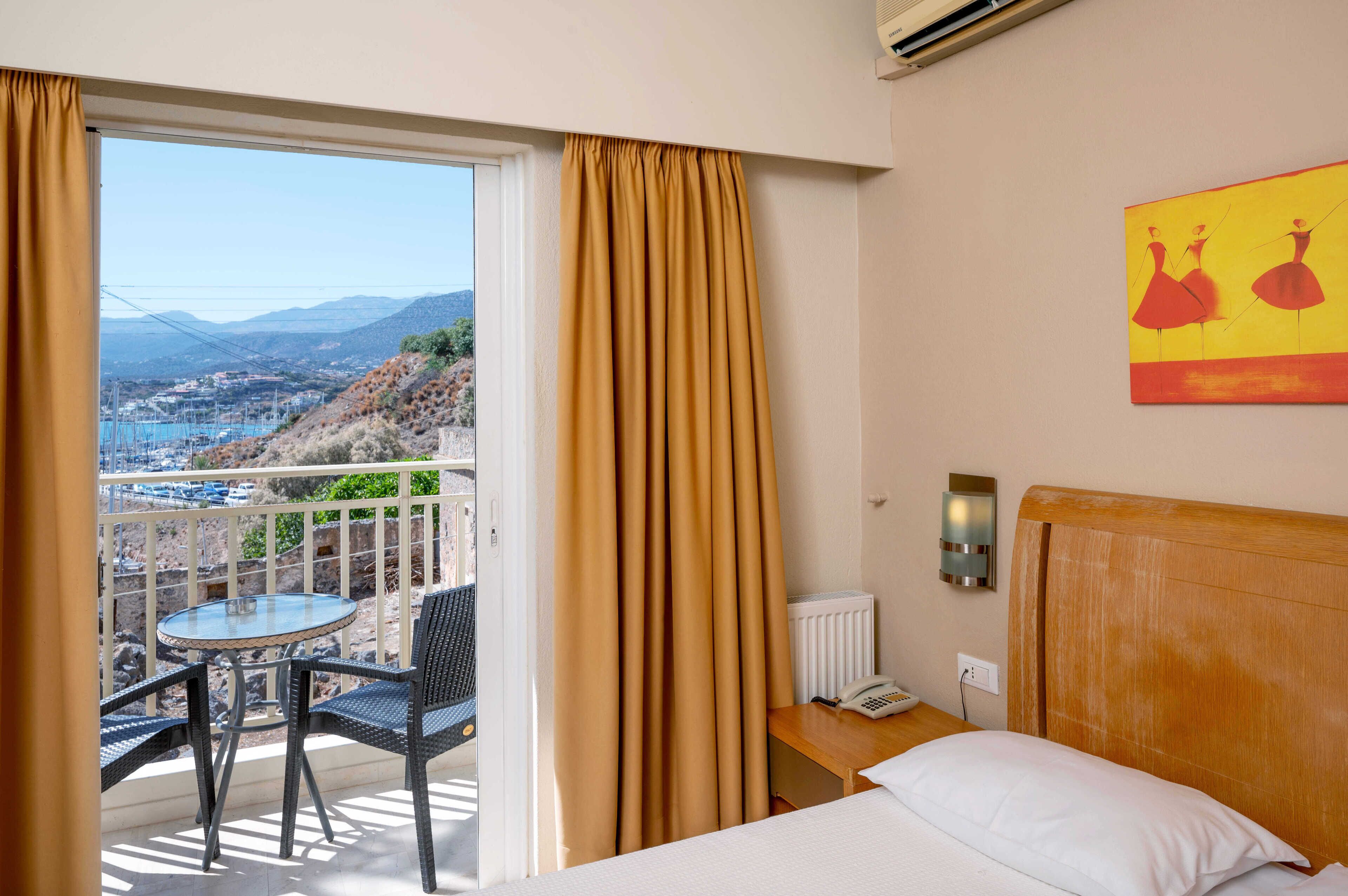 Une chambre d’hôtel avec un balcon, un lit, une table et un tableau.