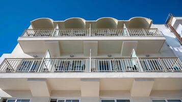 A multi-story building with balconies, large windows, and a clear blue sky.