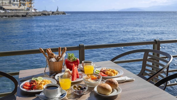 Una mesa con alimentos para el desayuno y vista al mar.