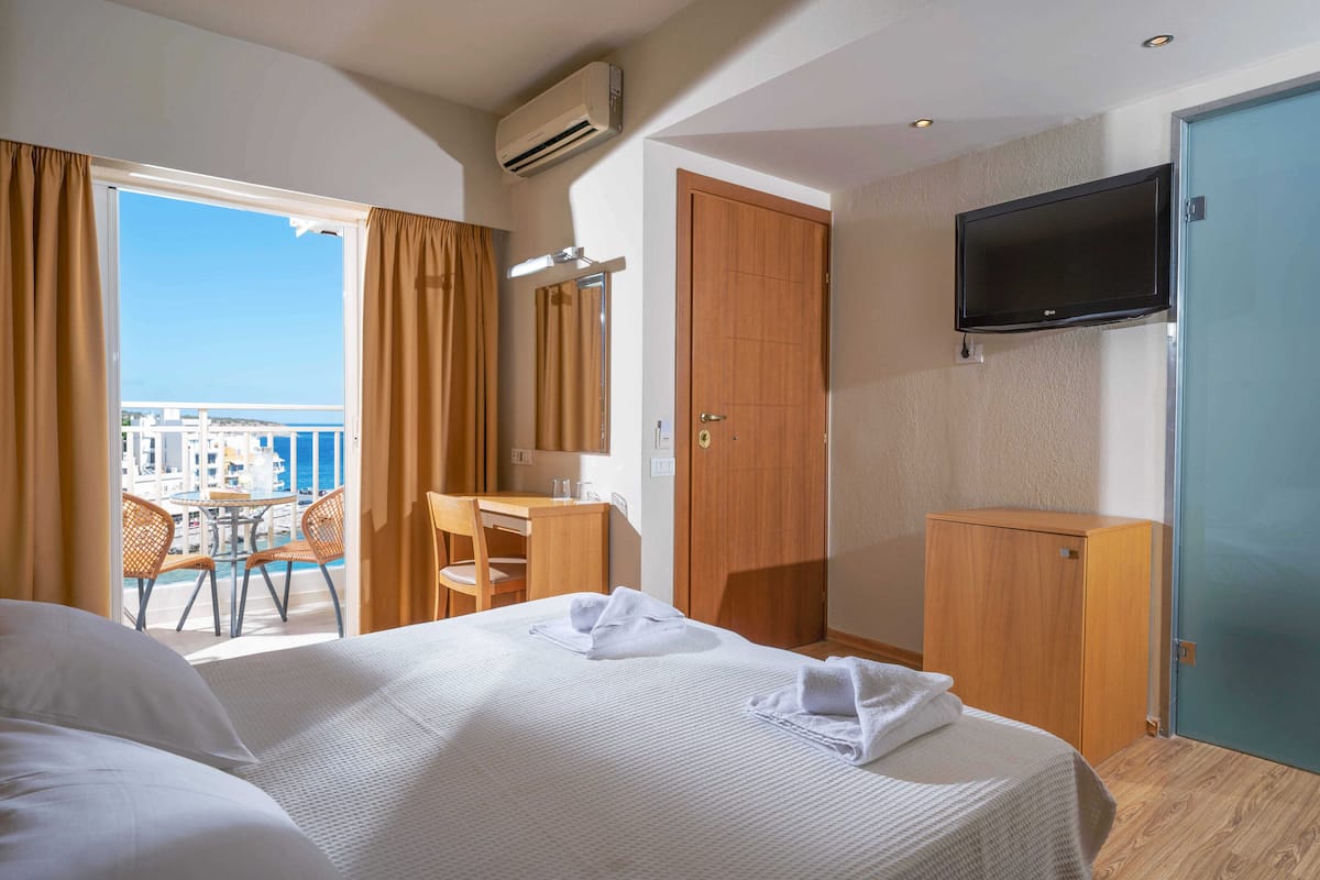 Ein Hotelzimmer mit Bett, Schreibtisch, Stuhl, Kleiderschrank und Fernseher.