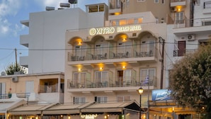 Un hotel frente a la playa con varios balcones, mobiliario exterior y un cartel que dice "KITRO BEACH HOTEL".