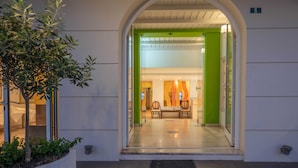 Una entrada con puerta de vidrio, mostrador de recepción y una pared verde en el interior.