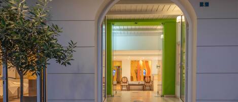 An entrance with a glass door, a reception desk, and a green wall inside.