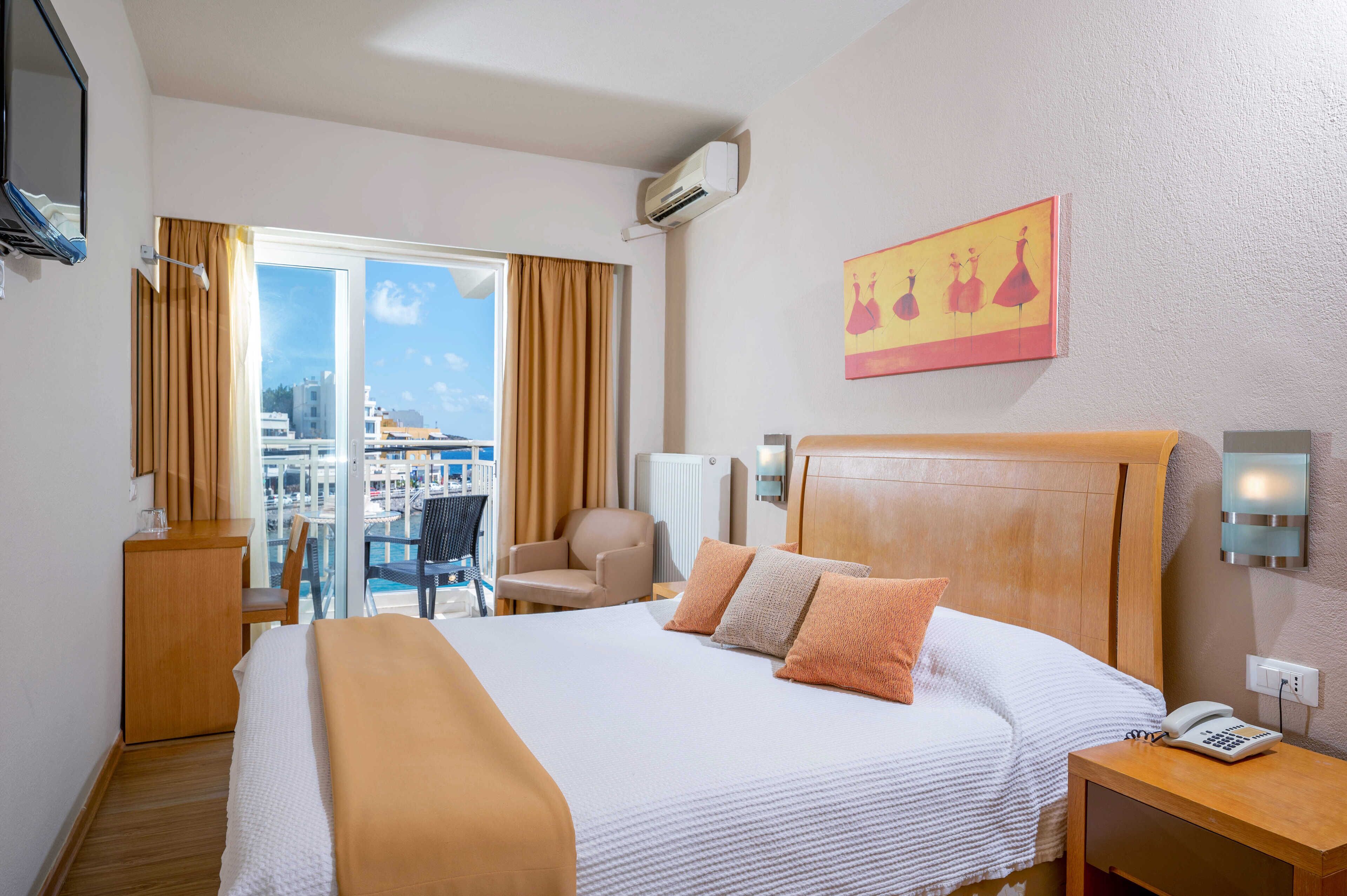 Hotelkamer met een groot bed, een bureau, een stoel en uitzicht op de stad door een groot raam.