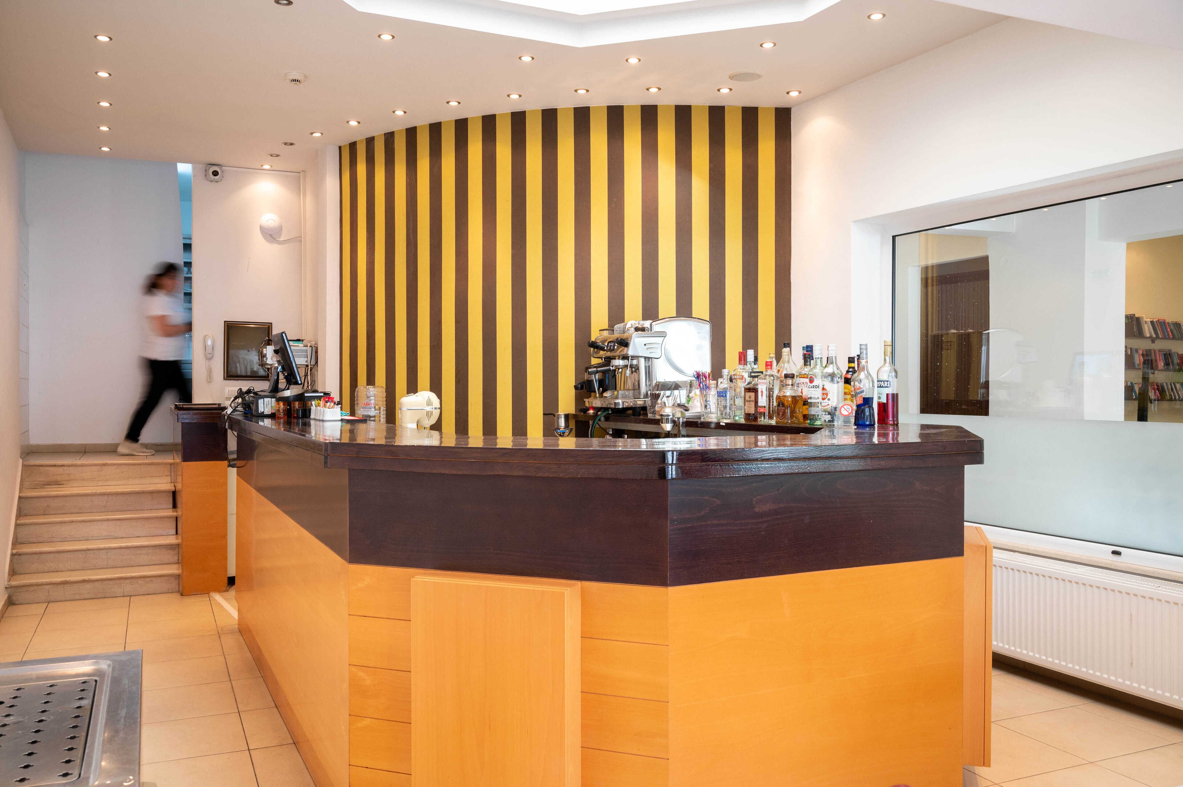 Un área de recepción moderna con una recepción curva, una cafetera y varias botellas.