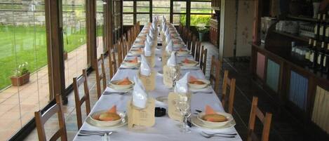 Una larga mesa de comedor lista para una comida, con manteles blancos, platos y vasos.