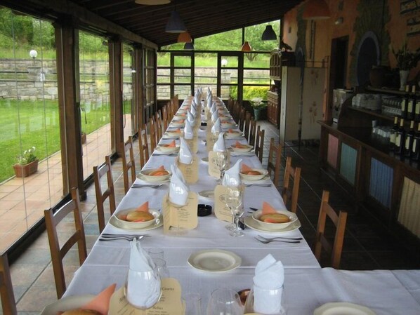 Una larga mesa de comedor lista para una comida, con manteles blancos, platos y vasos.