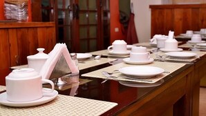 A dining area with multiple tables set with white tableware, including plates, cups, and cutlery. - Mallqui Hostal (Cusco)