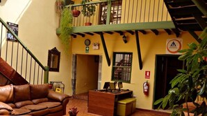 A cozy interior with a brown leather sofa, a wooden desk, and a staircase. - Mallqui Hostal (Cusco)
