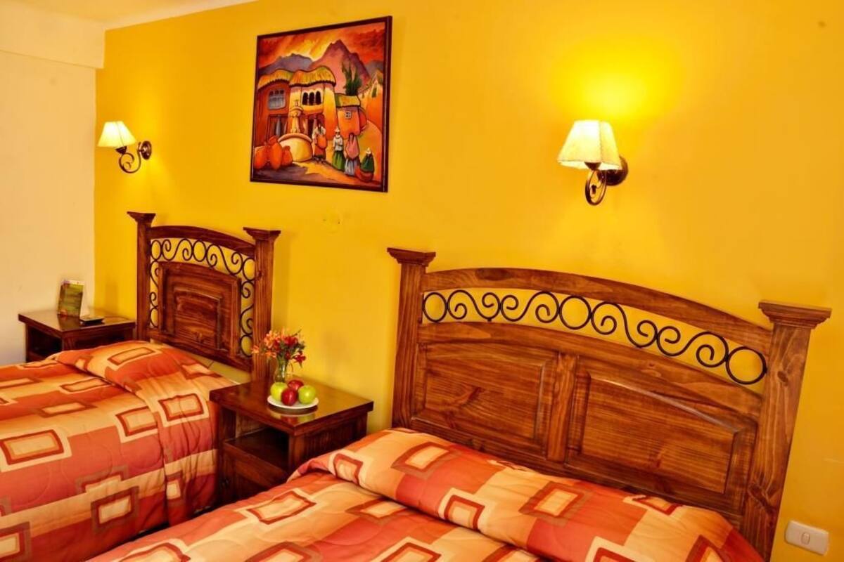 A hotel room with two wooden beds, a nightstand with a lamp, and a painting on the wall.