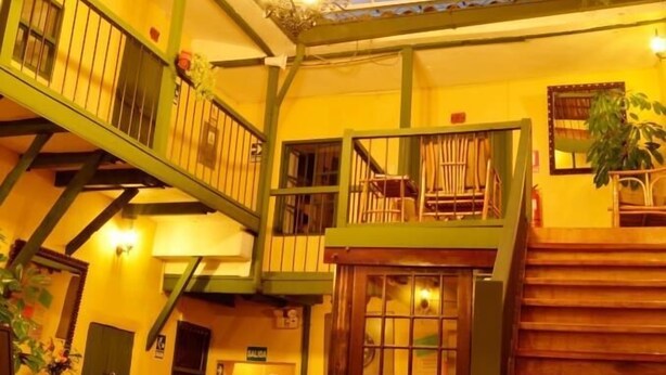 A spacious interior with a high ceiling, a glass skylight, and a staircase leading to an upper level. - Mallqui Hostal (Cusco)