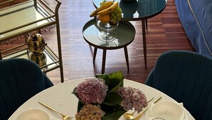 Taula de dinar a punt, amb diverses pastes, un got de llet i un ram de flors.