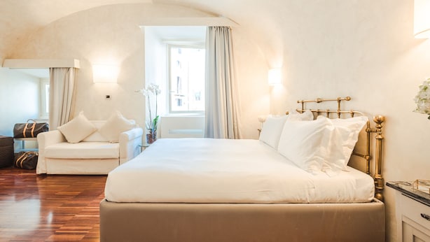 Habitació d'hotel amb un llit gran, un sofà i una finestra amb cortines.