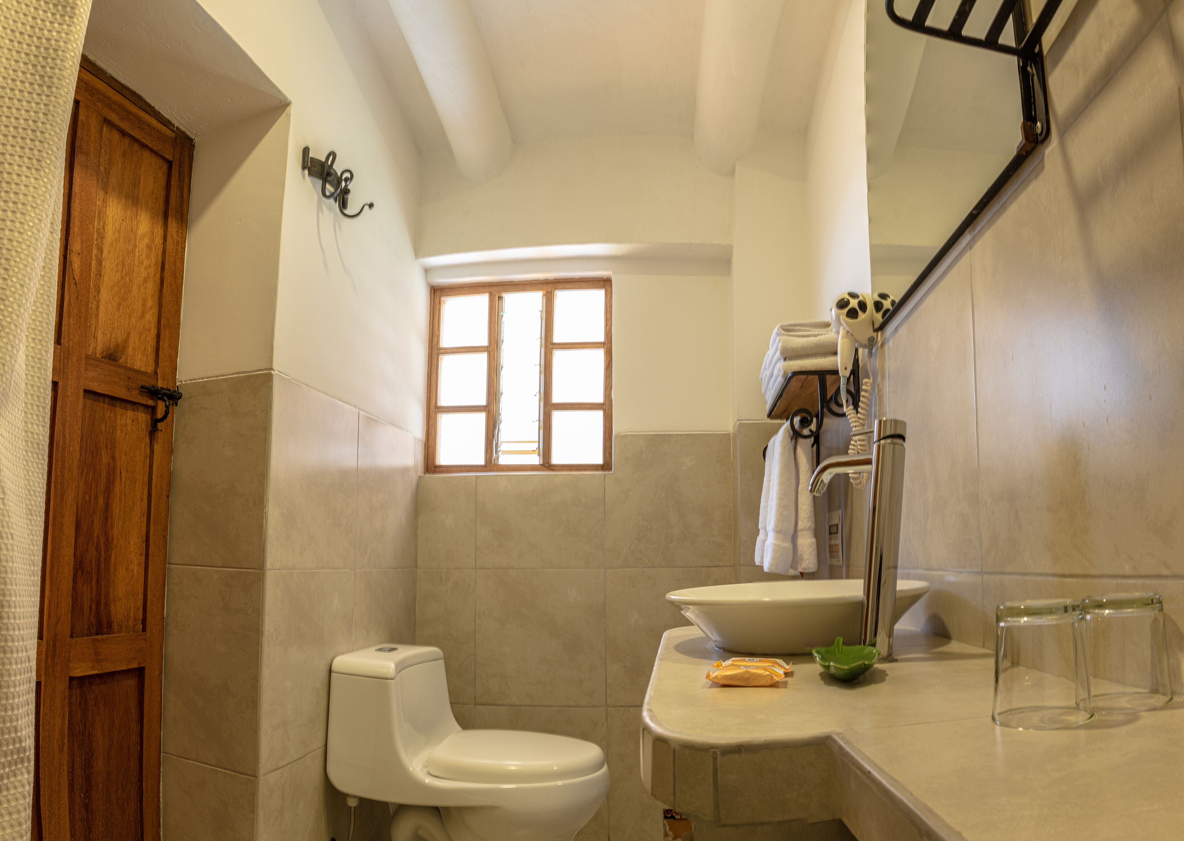 A bathroom with a toilet, sink, and window.