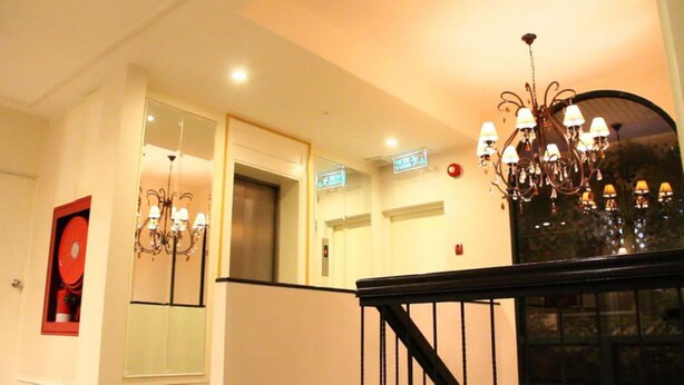 Eine Hotelhalle mit Treppe, einer Kristallleuchtre und einem Aufzug.
