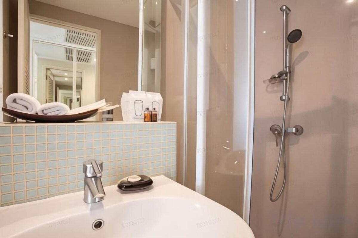 A bathroom with a sink, mirror, and shower.