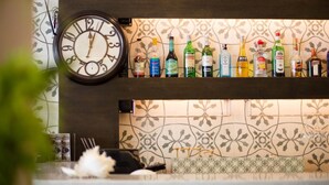 Eine Bar mit einer Uhr, verschiedenen Spirituosenflaschen und einer Wand mit Muster.