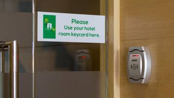 A hotel room door with a sign instructing to use the room keycard and a keycard reader.