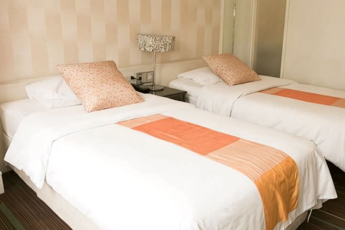 Une chambre d’hôtel avec deux lits, une table de chevet et une lampe.
