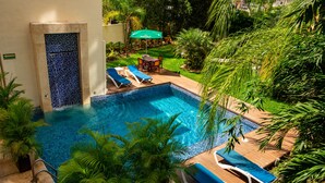 Une piscine avec des chaises longues, une table et un parasol.