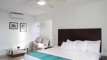 A hotel room with a bed, a ceiling fan, a bedside table, a chair, and a wall-mounted phone.