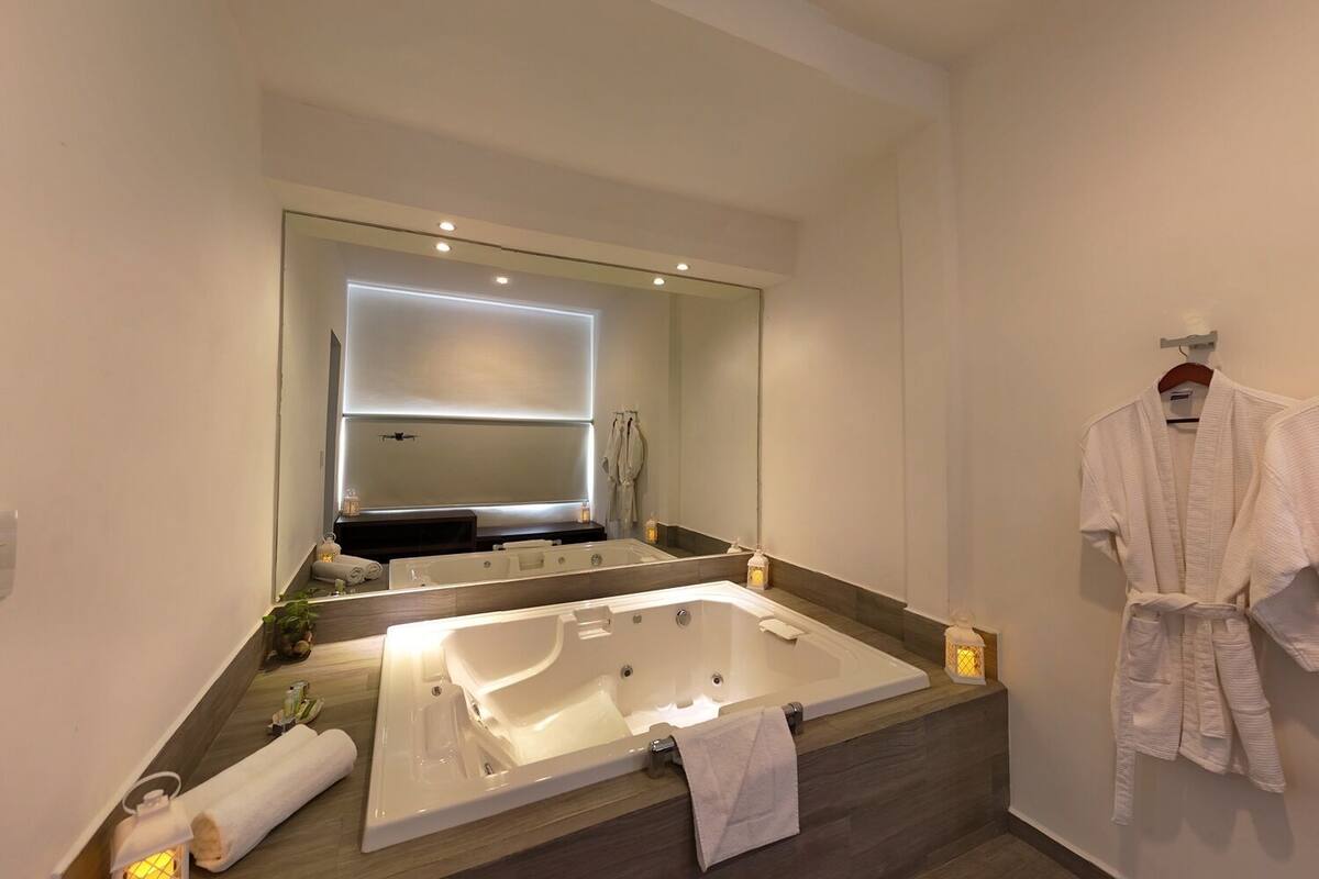 Un baño moderno con una bañera grande, un espejo y un perchero para bata.
