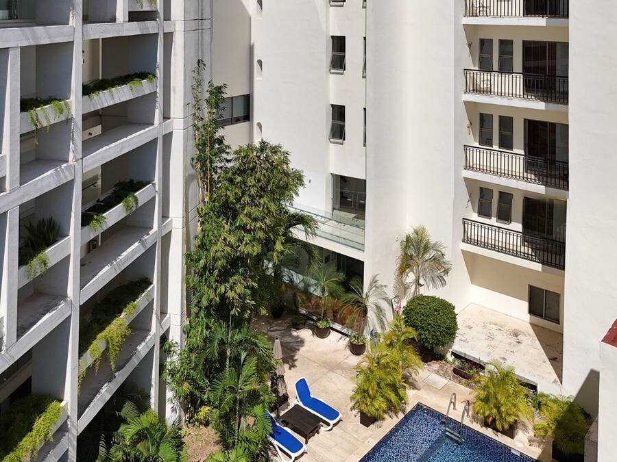 Ein modernes Hotel mit mehreren Etagen, Balkonen und einem Poolbereich.