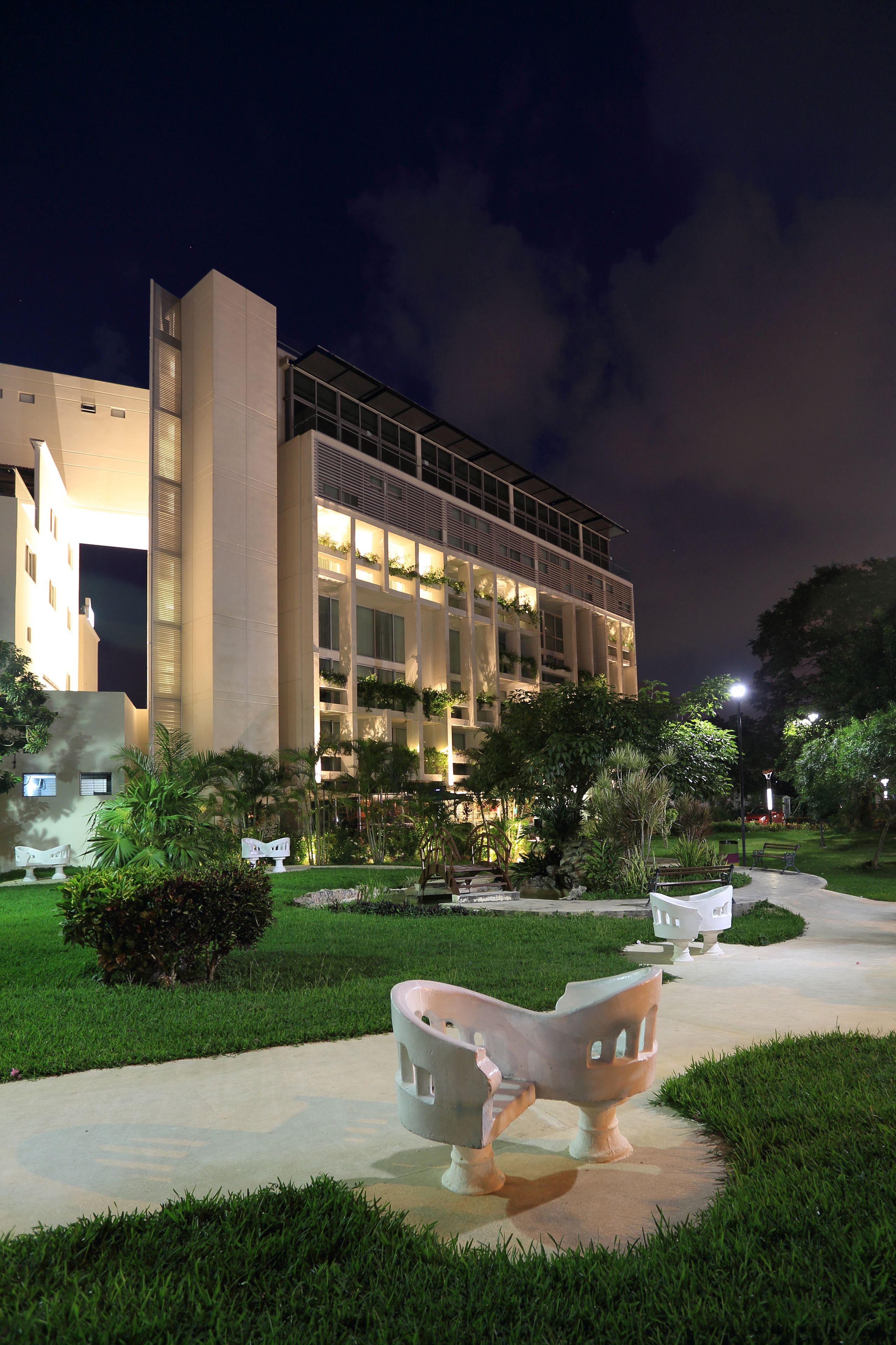 A modern building with a large entrance and a well-lit pathway leading to it.
