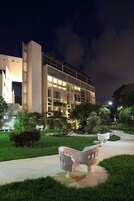 A modern building with a large entrance and a well-lit pathway leading to it.