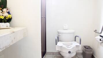 A small bathroom with a toilet, a trash can, and a sink with a towel dispenser.