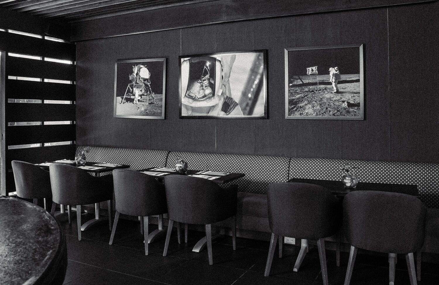 En restaurang med en inredd sittgrupp i form av bås, högt i tak och inramade tavlor på väggen.