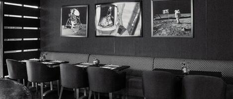 En restaurang med en inredd sittgrupp i form av bås, högt i tak och inramade tavlor på väggen.