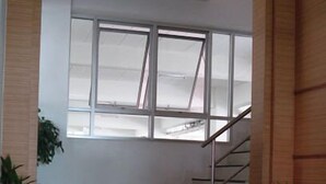 A staircase leading to a landing with a large window above. - Thanaplace Jaran 34 (Bangkok)