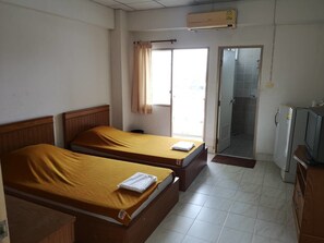Habitación de hotel con dos camas, televisión, refrigerador y baño con ducha e inodoro.