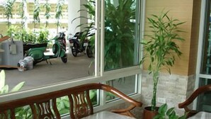 A wooden bench with a cushioned seat, a glass-top table with magazines, and a potted plant. - Thanaplace Jaran 34 (Bangkok)