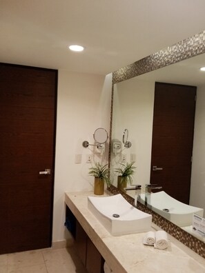 A modern bathroom with two sinks, a large mirror, and a towel rack.