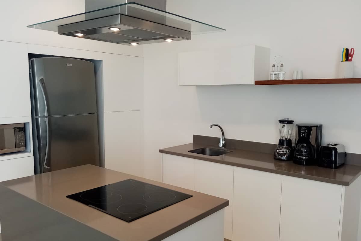 Una cocina moderna con refrigerador empotrado, isla con estufa, un lavamanos y una cafetera.