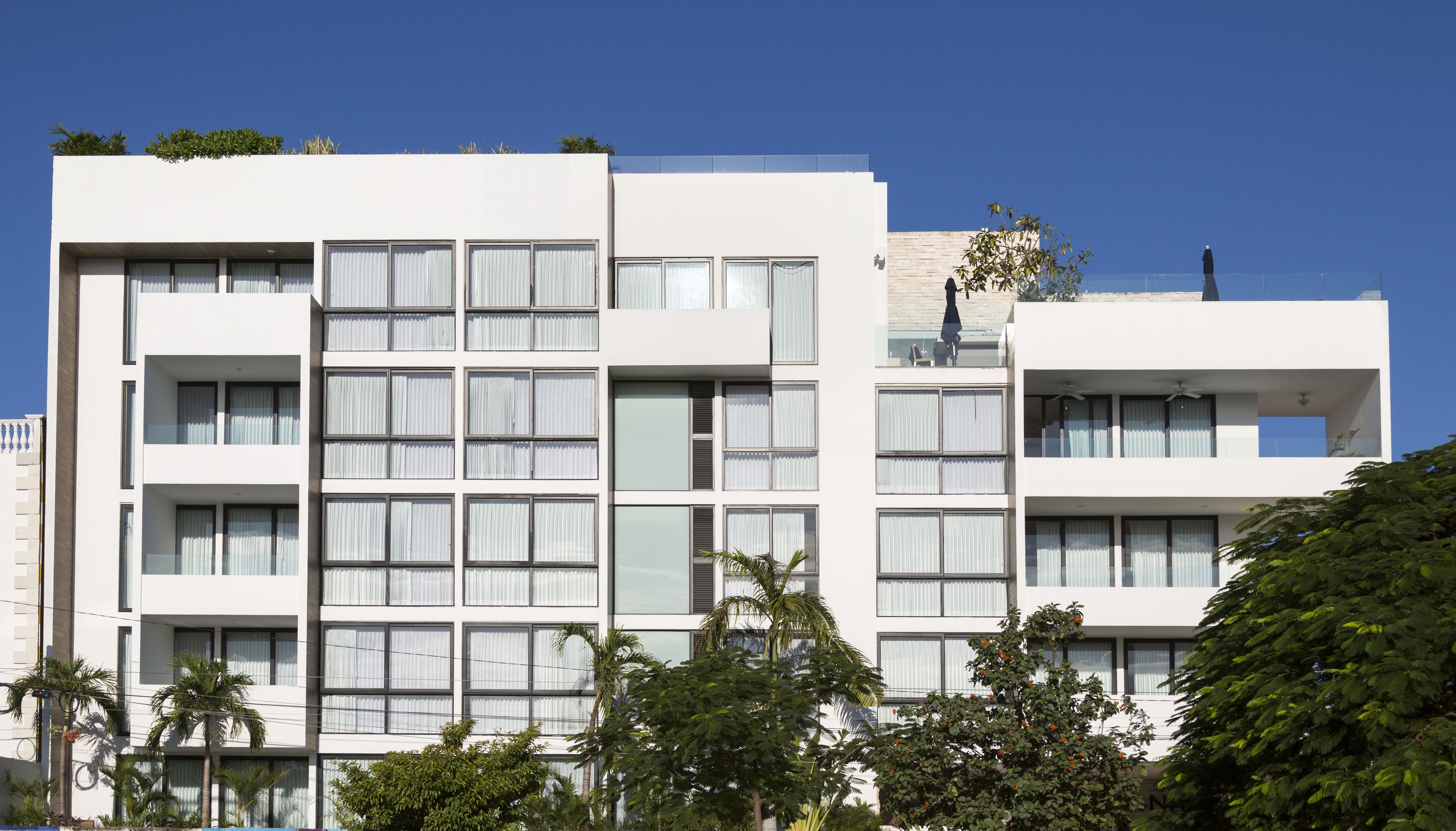 Un edificio moderno de varios pisos con fachada plana, ventanas grandes y balcones.