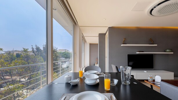 Un espace repas moderne doté d’une grande fenêtre, d’un téléviseur à écran plat et d’un décor minimaliste.