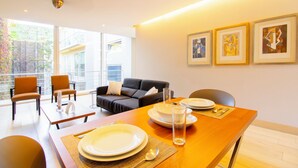 Un espace repas moderne avec une table en bois dressée pour quatre personnes, un canapé et un balcon offrant une vue agréable.