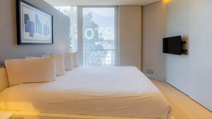 Une chambre d’hôtel moderne avec un grand lit, un téléviseur fixé au mur et une œuvre d’art encadrée accrochée au mur.