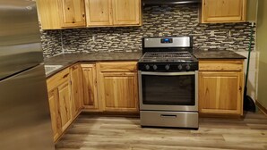 Una cocina con armarios de madera, un refrigerador de acero inoxidable, una estufa negra y un salpicadero de azulejos.