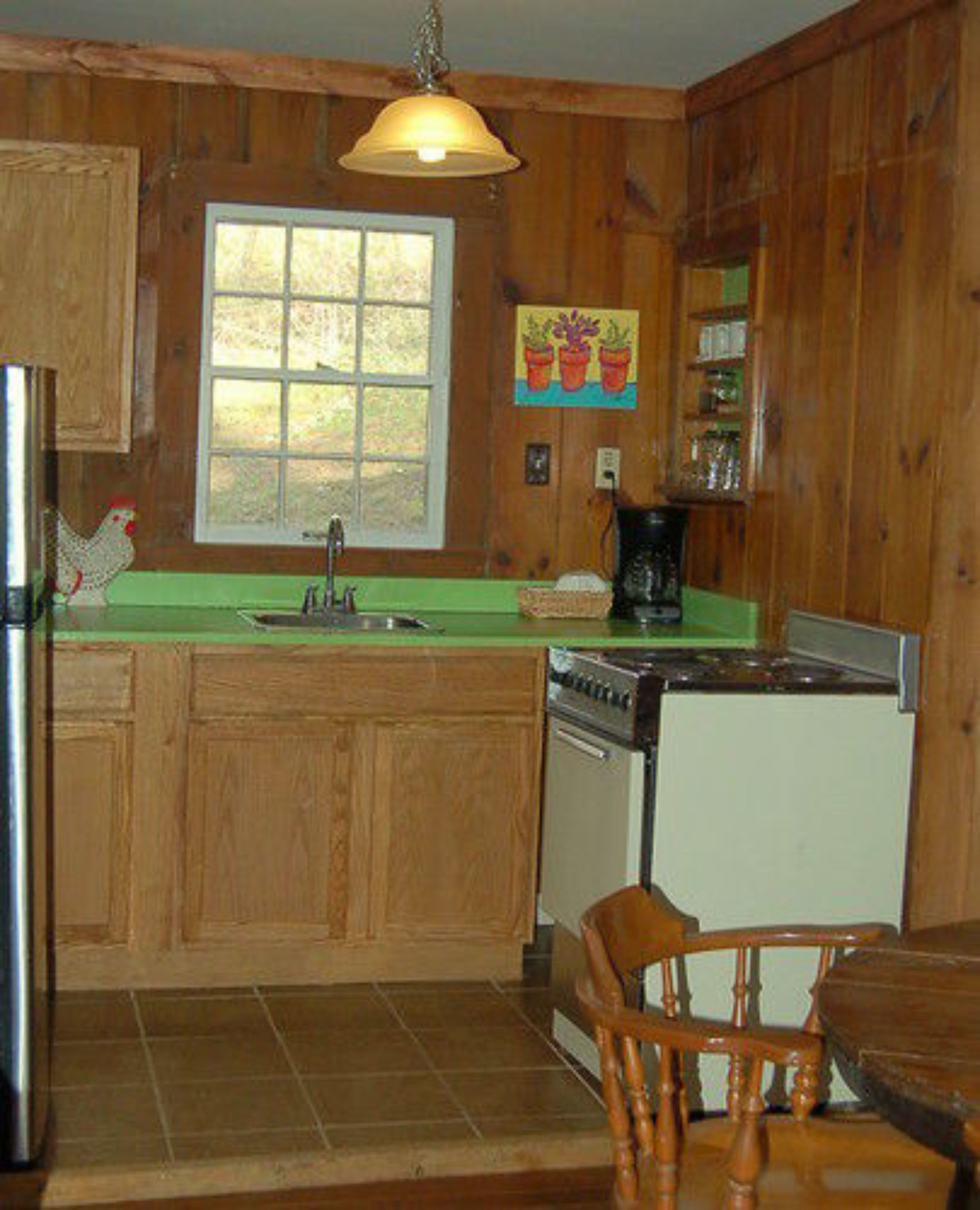 A wooden cabin-style kitchen with a central island, a sink, a stove, and a dining table with chairs.