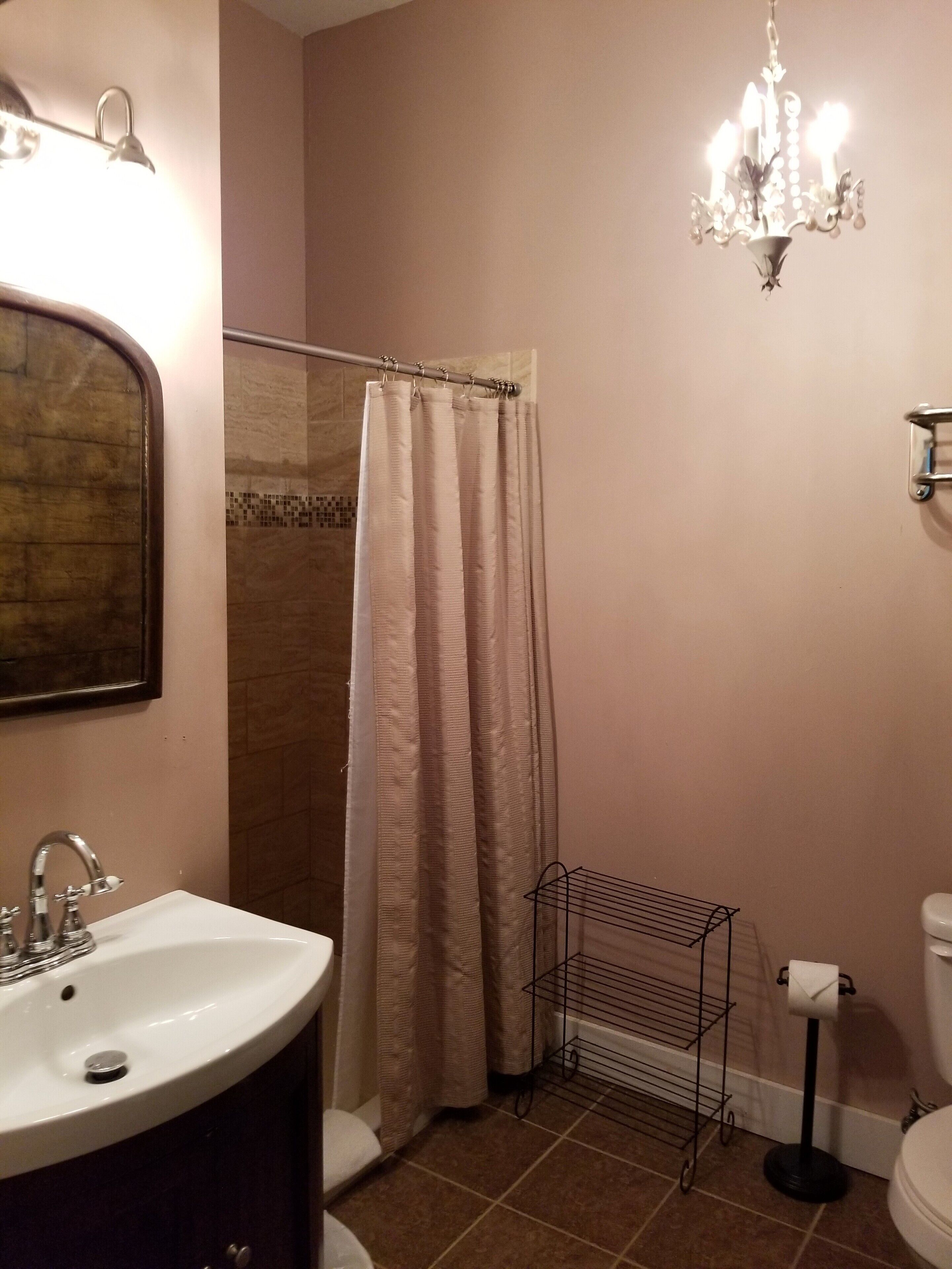Ein Badezimmer mit Duschvorhang, Waschbecken, Toilette und einer Kristallleuchtre.