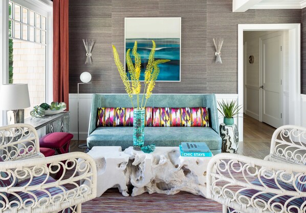 A living room with a teal sofa, white wicker chairs, a white coffee table, and a wall-mounted painting. - The Sydney, The Edgartown Collection (Edgartown)