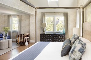 A hotel room with a large bed, a wooden chair, a small table, and a window with curtains. - The Sydney, The Edgartown Collection (Edgartown)