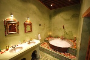 A bathroom with two sinks, a bathtub, and decorative elements like flower petals on the floor. - Riad Dar Benares (Fes)