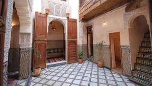A courtyard with a tiled floor, wooden doorways, and a staircase. - Riad Dar Benares (Fes)