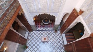An ornate courtyard with a tiled floor, a central fountain, and wooden arches. - Riad Dar Benares (Fes)