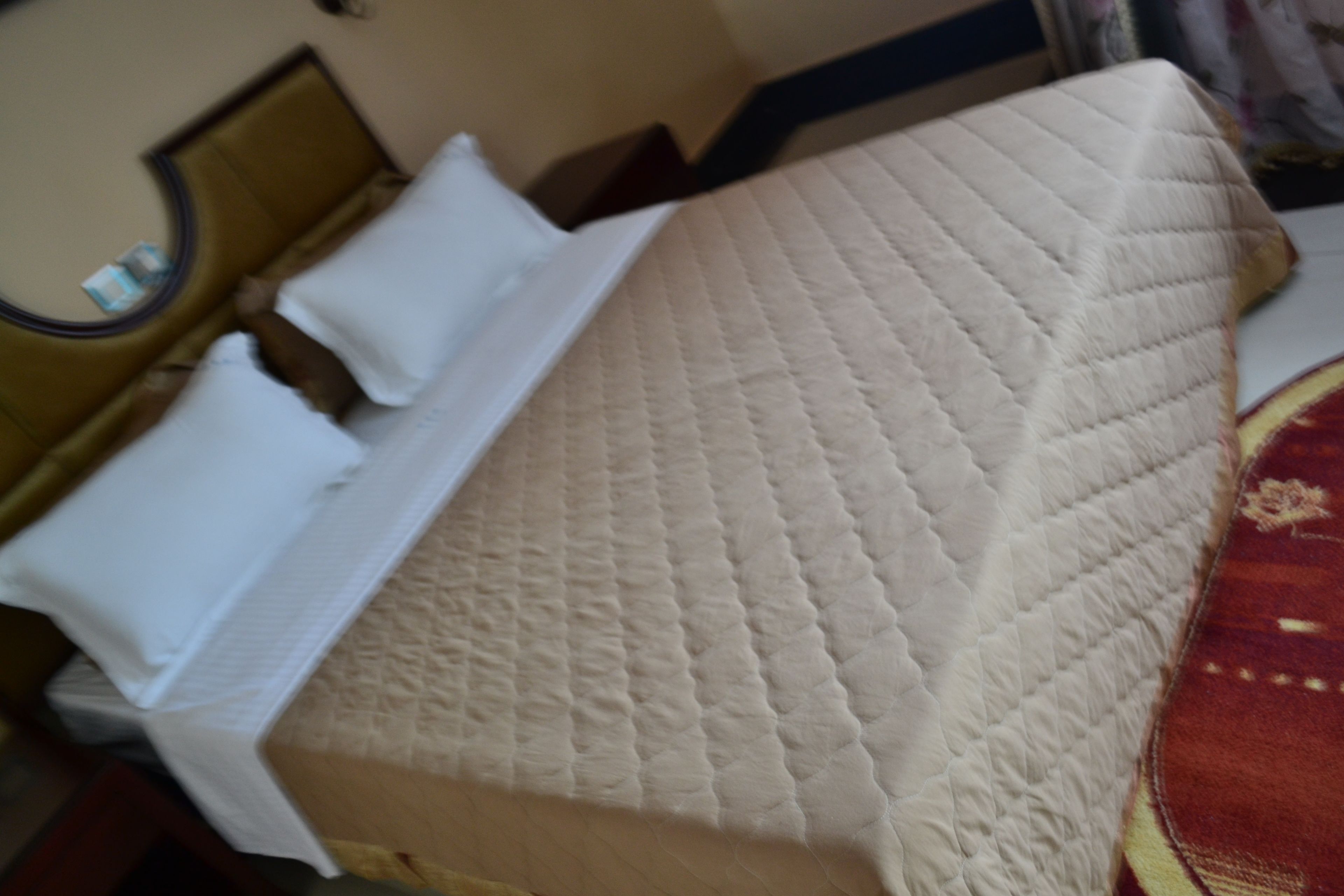 A bed with a quilted mattress, white pillows, and a headboard.